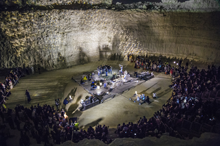 ENGAGE Public School for Social Engagement in Artistic Research, Ilaria Lupo, Nocturne for Pit Orchestra, 2017
Nocturne for Pit Orchestra è una performance sonora concepita per la Miniera Nazionale del Bahrain eseguita dai lavoratori del sito. Il progetto affronta le dinamiche del fare musica nella cornice lavorativa e allo stesso tempo mira a esplorare i livelli intrecciati che connettono l'identità della cava con i cambiamenti socio-economici nel Bahrein del XX secolo e nella regione del Golfo. I Fidjeri (canzoni dei pescatori di perle) incarnano una fondamentale storia del lavoro nel Golfo proprio prima dell'era del petrolio, comprendendo al contempo miscele e fusioni dai bacini levantini, persiani, dell'Africa orientale e dell'Asia meridionale. Il musicista Rabih Beaini ha coinvolto l'equipaggio di lavoratori in un processo in cui una serie di influenze sono state esplorate e combinate. La performance finale si è svolta nella stessa cava, svolgendosi come un processo che passa tra dissonanza e armonia.