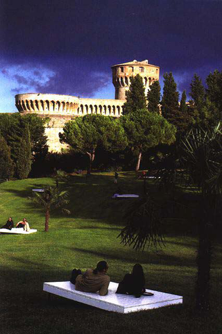 Vito Acconci. Arte, architettura e design verso lo spazio pubblico - Un confronto con la situazione della Public Art in Italia nel lavoro di 60 artisti italiani. Conferenza di Vito Acconci 14 aprile, BERT THEIS,  LE DITA DELLA MANO,  PARCO FIUMI, VOLTERRA, 1998

1. Progetto
Inserire dieci isolette verniciate di bianco con altrettante palme nel parco Fiumi. Tracciare ogni sera dopo il tramonto un segno bianco nel cielo sopra Volterra. Creare un elemento sonoro legato a questi due elementi.
2. Un dubbio
Una settimana fa il direttore di un museo spagnolo mi ha confidato di non aver mai letto una sola riga di tutti i cataloghi che lui stesso ha fatto pubblicare negli ultimi dieci anni. Supponiamo comunque di avere una lettrice o un lettore che non si siano fatti scoraggiare dalla marea di testi decorativi e inutili che ci sono in giro, che cosa può dare loro un testo? Quale è il rapporto che intercorre tra opera, mostra e testo, è infatti noto che il vero artista non dice mai la verità ( Bert Theis, true artist , progetto P.O. Box, Mamco, Ginevra).
3. Un giorno come gli altri
Lunedì 27 luglio 1998 sull'aereo Francoforte-Firenze leggo le seguenti notizie: in Nuova Guinea la gigantesca onda causata da un maremoto ha ucciso più di 700 persone. In Germania negli ultimi anni sono nate 220 ditte di biotecnologia create da scienziati per ricavare un vantaggio economico dalle scoperte scientifiche. A Nuova Delhi il numero dei casi di colera è in aumento. La macchina per scrivere di Nietzsche misura 23 cm. di altezza e 27 di larghezza. Una macchia di petrolio sulla costa sud del Brasile ha fatto una strage di centinaia di pinguini. In Israele il temuto  hacker  Ehud Tenenbaum lavora adesso per l'esercito e fa pubblicità per una ditta di computer. In Honduras un gruppo di indiani ha distrutto una statua di Cristoforo Colombo. Lo scienziato Lee Silver non vede nessun problema filosofico nel produrre esseri umani senza testa per prelevarne gli organi. Nel mondo arabo i casi di violazione dei diritti umani si moltiplicano. Sulle spiagge italiane i vicini di ombrellone si guardano ma non si parlano. In un testo intitolato Achieving our Country, il filosofo americano Richard Rorty fa l'elogio dell'orgoglio nazionale. Dall'inizio delle ostilità, in febbraio, i morti serbi e albanesi in Kosovo sono 460. A Orange, in Francia, sono state profanate 50 tombe nel cimitero ebraico.
Improvvisamente mi viene in mente la scena finale del film  Underground  di Kusturica, dove i protagonisti si ritrovano tutti insieme su un pezzo di terra che si sta staccando dalla terraferma.
4. Un fax a Florian
Lieber 10 Palmen als 1000 Eichen! (Meglio dieci palme che mille quercie!)
5. Uno scongiuro etrusco
Il secondo giorno sono ritornato da solo a Volterra. Una visita più attenta al Museo Etrusco ha confermato il sospetto venutomi il giorno prima quando ero entrato con Angela, Florian e Marco nel parco Fiumi: la posizione archetipica in questo territorio è quella orizzontale. Non avevo mai visto tante sculture di uomini e donne in posizione di riposo. Il marito, sdraiato con la moglie sull'urna degli sposi, fa con le dita un gesto di scongiuro. Sta scongiurando tutti quelli che ci obbligano ad alzarci?
6.  Onde
Il nostro pianeta produce in continuazione un rumore di fondo: il rumore delle onde dei mari e degli oceani. Le onde marine producono onde sonore che si diffondono per tutta la terra. Il Teremin è uno strumento musicale inventato negli anni Venti nell'Unione Sovietica. Si suona muovendo le mani e le dita in un campo magnetico senza toccare niente. I Beach Boys l'hanno usato per la canzone Good Vibrations.
7.  Una domandaÈ ancora possibile una visione unitaria del mondo o dobbiamo accontentarci di un sapere frammentario, rinunciando a quello sforzo millenario dell'umanità di trovare una teoria unica che spieghi la totalità dell'universo? La genesi dipinta da Bartolo di Fredi sulle pareti della chiesa della collegiata a S. Gimignano illustra uno dei tentativi storici. Allo stato attuale la scienza non ci riesce più. La fisica, per esempio, definisce l'universo con due teorie, la teoria generale della relatività e la meccanica quantistica. Le due teorie si escludono a vicenda. Se la prima è vera, la seconda è sbagliata e viceversa. Possiamo dedurne che la verità in questo momento storico non è più riducibile a un'unica piattaforma, a un grande racconto unico, ma sia costituita piuttosto da una moltitudine di frammenti, di "quark" di verità sparsi qua e là nel paesaggio del pensiero umano come altrettante isolette?
8. Il cielo visto da una cella
"Per dirigere un carcere, bisogna anche essere un artista". Quest'affermazione del Direttore della casa di pena di Volterra merita senz'altro di essere meditata più a lungo. Mi ha colpito la vicinanza di due realtà sociali radicalmente diverse: se da un lato il parco con la sua atmosfera serena di pace e subito accanto la sua antitesi, la fortezza-galera. Il mio desiderio di fare un'opera che legasse queste due situazioni è stato parzialmente ostacolato dal rifiuto del Direttore del carcere di trasformare una guardia armata sulle mura della fortezza in artificiere che sparasse a ogni tramonto un segnale di luce bianco nel cielo sopra Volterra. Una guardia armata che fa un gesto d'arte perderebbe probabilmente la sua funzione di minaccia nei riguardi dei detenuti. Nel carcere l'arte entra solo se non ne cambia minimamente le regole. Ma qual è la funzione dell'arte?
9.  Sotto il regno di Dioneo
"Le piagge delle quali montagnette così digradando giuso verso il pian discendevano, come ne’ teatri veggiamo dalla lor sommità i gradi infino venire successivamente ordinati sempre ristignendo il cerchio loro [...] Quindi, essendo in più luoghi per la piccola valle fatti letti e tutti dal discreto siniscalco di sarge francesce e di capoletti intorniati e chiusi con licenza del re, a cui piacque, si poté andare a dormire; e chi dormir non volle, degli altri loro diletti usati pigliar poteva a suo piacere." (G. Boccaccio,  Il Decameron)
10.  Il quinto giorno
Ritorno da Volterrra a San Gimignano. Ritorno alla chiesa della Collegiata per studiare ancora le storie del Vecchio Testamento di Bartolo di Fredi. Non c'è più ombra di dubbio: nel paradiso l'uomo nasce sdraiato, nudo sotto una palma.

(Bert Theis, in  Arte all'Arte , catalogo mostra, Siena, a cura di Florian Matzner e Angela Vettese, 1998).