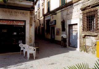 Vito Acconci. Arte, architettura e design verso lo spazio pubblico - Un confronto con la situazione della Public Art in Italia nel lavoro di 60 artisti italiani. Conferenza di Vito Acconci 14 aprile, CESARE PIETROIUSTI -  ZAGAROLO - GALLICANO - S. CESAREO - ZAGAROLO 28 AGOSTO - 18 SETTEMBRE 1998

Organizzare in un certo posto un percorso (con pullman e guida turistica che illustra i luoghi) attraverso zone periferiche fuori dagli usuali circuiti turistici. Studiare dettagliatamente le caratteristiche dei luoghi per i quali si passa. Quando è stata fatta la strada, chi è l'architetto che ha progettato il palazzo, chi vi ha vissuto, per che cosa è stato usato quel determinato locale, cosa è successo di rilevante (fatti di cronaca, o eventi statisticamente interessanti) e che cosa sta succedendo attualmente in tali luoghi. Trattare il luogo e organizzare la visita turistica con le stesse modalità usate per visitare e illustrare i luoghi monumentali (1997).
Ho realizzato questo progetto per la mostra  Stradarolo '98 - arte e spettacolo sulle vie dei pendolari (18-19-20 settembre 1998) che si è svolta in diversi siti a Genazzano e Zagarolo (Roma), sul percorso stradale fra i due paesi (e paesi limitrofi), nonché sugli autobus di linea Cotral lungo lo stesso percorso.
Il mio intervento si è svolto su alcuni degli autobus ed è consistito in una guida a 13 luoghi "qualunque" individuati lungo il tratto Zagarolo-Gallicano-San Cesareo-Zagarolo, con le relative storie, tratte da racconti di numerose persone del posto, senza la cui collaborazione questo progetto non si sarebbe attuato.
La disponibilità delle persone che ho incontrato - fra il 28 agosto e il 18 settembre 1998 - non si è manifestata soltanto nel raccontarmi ciò di cui erano a conoscenza, ma anche nell'indicarmi altre persone che, su qualche argomento specifico, fossero ritenute a loro volta più "competenti", ovvero in possesso di conoscenze (possesso di dati, ricordi personali, storie raccontate da altri ecc.) non altrimenti accessibili.
Le conoscenze individuali qualunque, e il percorso "a diramazione" (fra una certa persona e un'altra indicata dalla prima perché "ne sa di più", e così via) nella ricostruzione di storie e avvenimenti, sono, a mio avviso e nella mia esperienza, i temi di questo lavoro.
Luoghi individuati (e storie relative): Il tunnel di via del Formale; Il campo sportivo e la squadra di pallavolo; Il depuratore inattivo; Il deposito di materiale bellico; L'incrocio della pompa abbandonata; Il pratino conviviale; I soprannomi dei buccalitti; Il meccanico contestato; S. Cesareo comune!; Il ripostiglio di Augusto; Il bosco dell'amore e dell'ergastolano; I tordi matti.

I soprannomi dei "Buccalitti"
Non è chiaro il motivo, ma gli abitanti di Zagarolo chiamano quelli di Gallicano "Buccalitti" (derivazione da boccale, o da boccone? Quindi o legato al bere, o al mangiare, o alla credulità). Peraltro, a Gallicano qualcuno mi ha detto che i gallicanesi restituiscono agli zagarolesi il medesimo soprannome, appena mutato in "Buccaletti".
A Gallicano, comunque, fra loro si chiamano tutti con un qualche soprannome. Al Bar dello Sport, noto in paese come il bar di Boccio e Pisello (i soprannomi dei due gestori soci in affari), la moglie di Boccio mi ha detto che è normale chiamarsi con il soprannome e che sul quaderno dei crediti dove lei segna le consumazioni di chi non paga lì per lì, tutti sono indicati con il soprannome. C'è "fontana", "gabbiano", "giuliètt", svazzer", gargiulo, pollarino, bellapalla, ecc. (ma nella zona il soprannome considerato più curioso è dello zagarolese Lorenzino "cazzubenignu").
I soprannomi dei padri ricadono sui figli. I due figli della signora del bar si chiamano Boccetto e Boccetta (sono i figli di Boccio). Il bar a poca distanza, Bar della Piazza o da Tonino è più noto come il bar di Mozzò perchè il barista - all'epoca compagno di scuola della moglie di Boccio - si mangiava le unghie.
Un altro bar, aperto da poco da qualcuno che viene da fuori, è privo di soprannomi.
Anche il panettiere sulla strada principale di Gallicano è noto come Boccio.